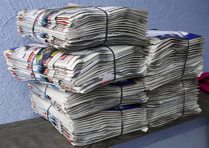 Stacks of bundled newspapers on a wooden surface