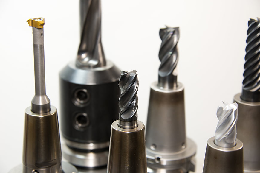 Assortment of CNC milling cutters and drill bits on white background