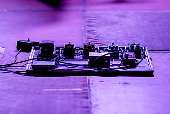 Guitar pedalboard on stage floor with purple lighting