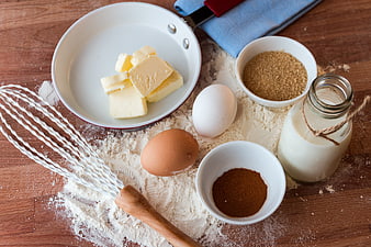 Baking ingredients with flour, eggs, butter, and cocoa on wooden table