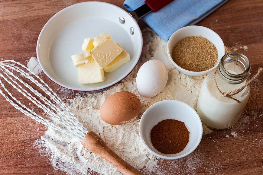 Baking ingredients with flour, eggs, butter, and cocoa on wooden table