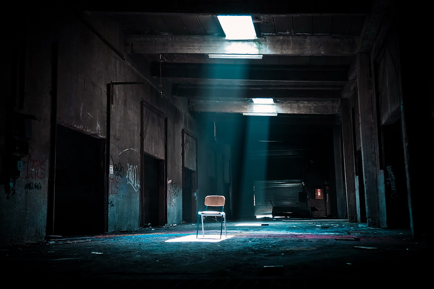 Lone Chair in Abandoned Factory with Dramatic Light Beams