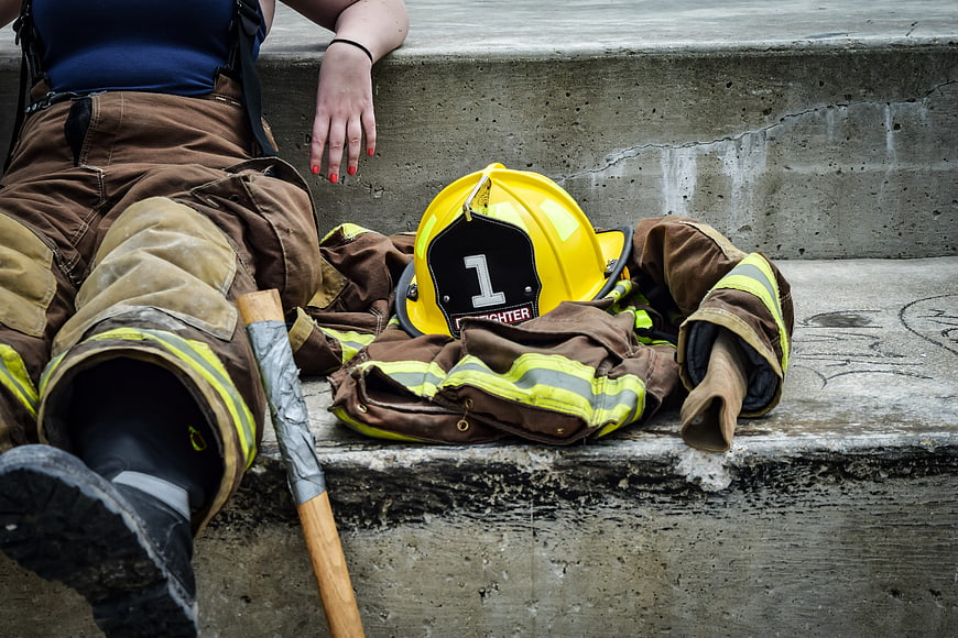 Female firefighter resting on concrete steps with gear
