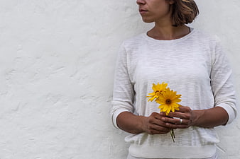 Woman holding yellow flowers against white wall