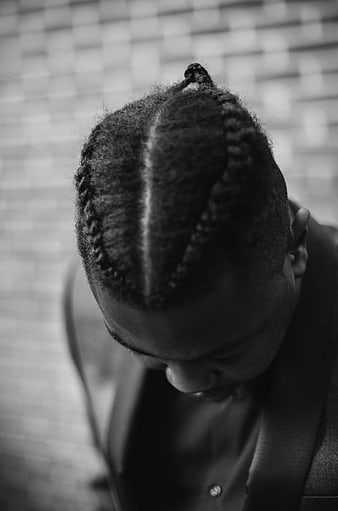 Black and white portrait of man with braided cornrows looking down