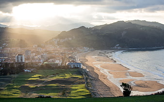 Sunlit coastal cityscape with golf course and sandy beach