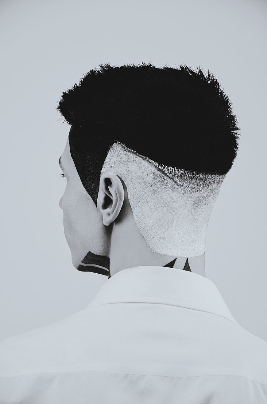 Black and white portrait of man with undercut haircut and neck tattoo
