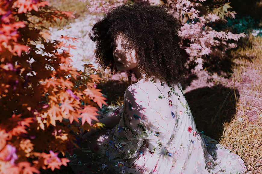 Woman with Curly Hair in Floral Dress Amongst Autumn Leaves