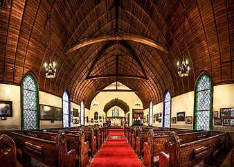 Interior of a wooden chapel with red carpet aisle and stained glass