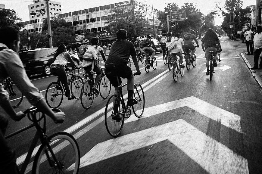Group of Cyclists Riding Down City Street in Black and White