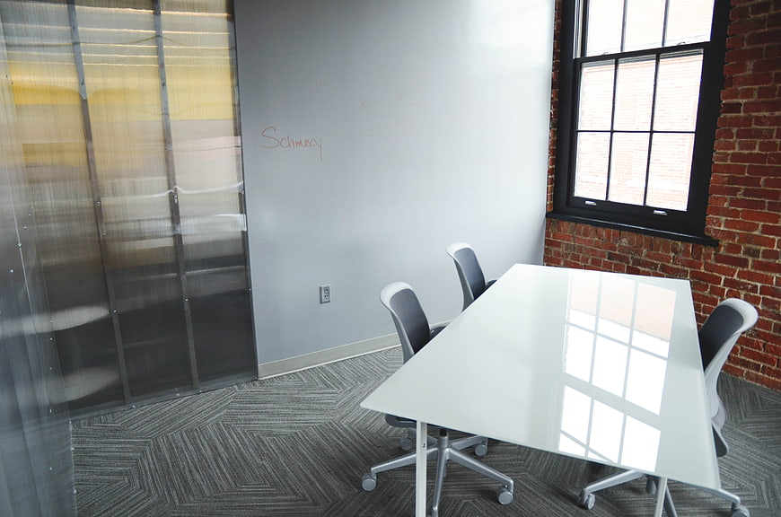 Modern office meeting room with white table and brick wall