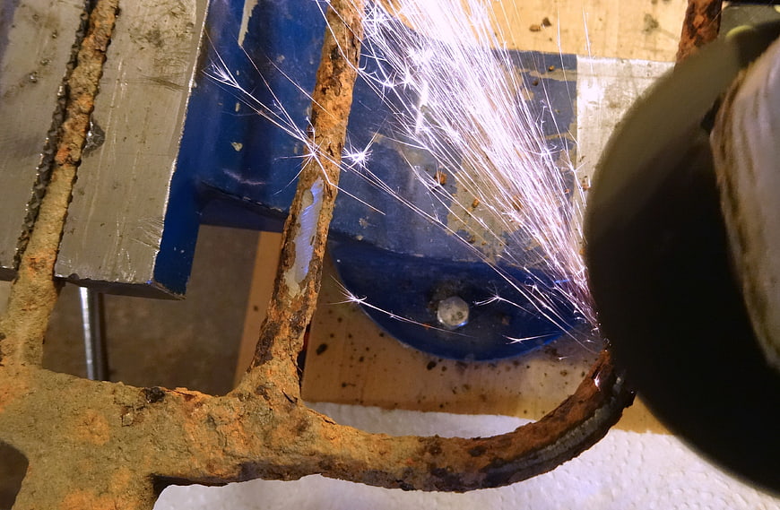 Close-up of angle grinder cutting rusty metal with sparks