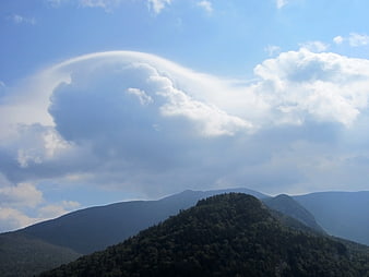 Lenticular cloud formation over green mountain ridge