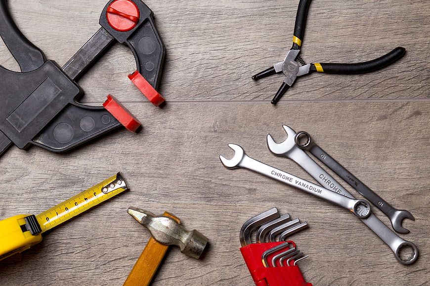 Top view of assorted hand tools on wooden background