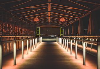 Empty illuminated pedestrian bridge at night with orange lights