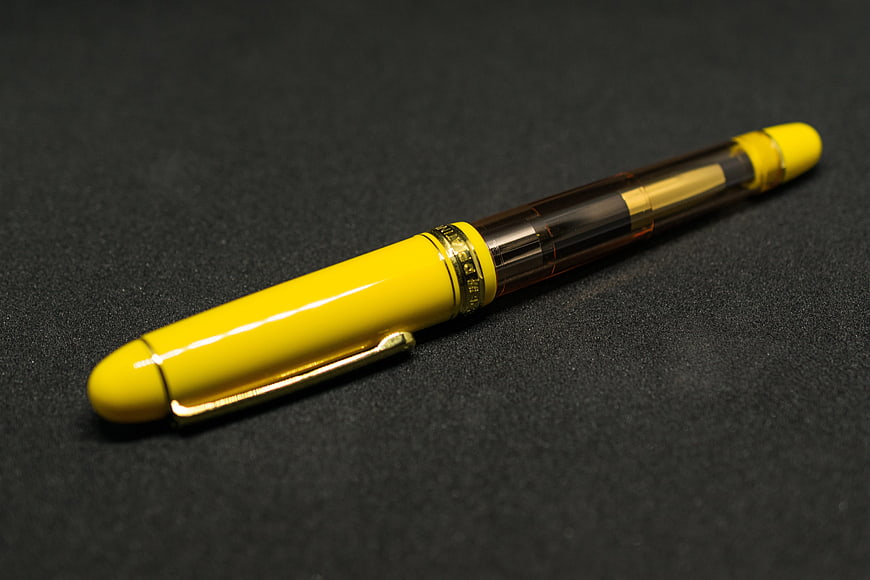 Yellow fountain pen on dark textured background