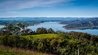 Panoramic View of Lake and Rolling Hills with Snowy Mountains
