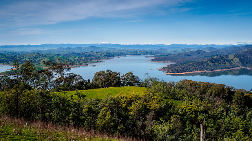 Panoramic View of Lake and Rolling Hills with Snowy Mountains