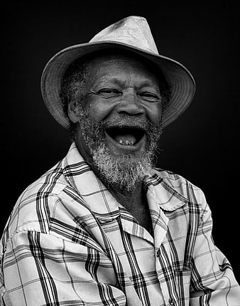 Black and white portrait of laughing senior man in hat