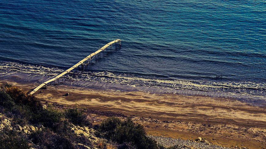 Aerial View of Wooden Jetty Extending into Blue Sea at Zapalo Beach