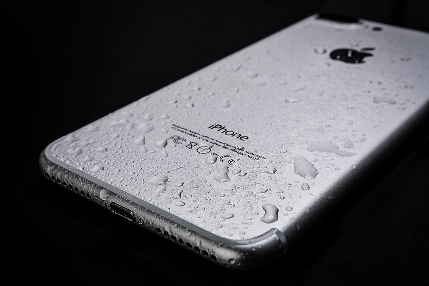 Close-up of wet silver iPhone on black background