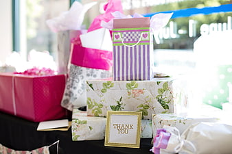 Stack of wrapped gifts with thank you sign on table