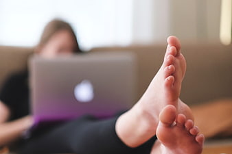 Relaxed woman using laptop with bare feet on couch