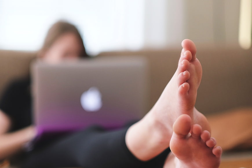 Relaxed woman using laptop with bare feet on couch