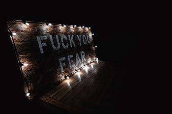 Motivational wooden sign with string lights in dark room