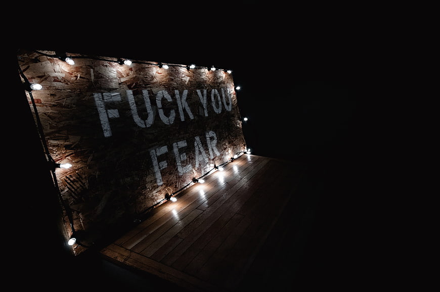 Motivational wooden sign with string lights in dark room