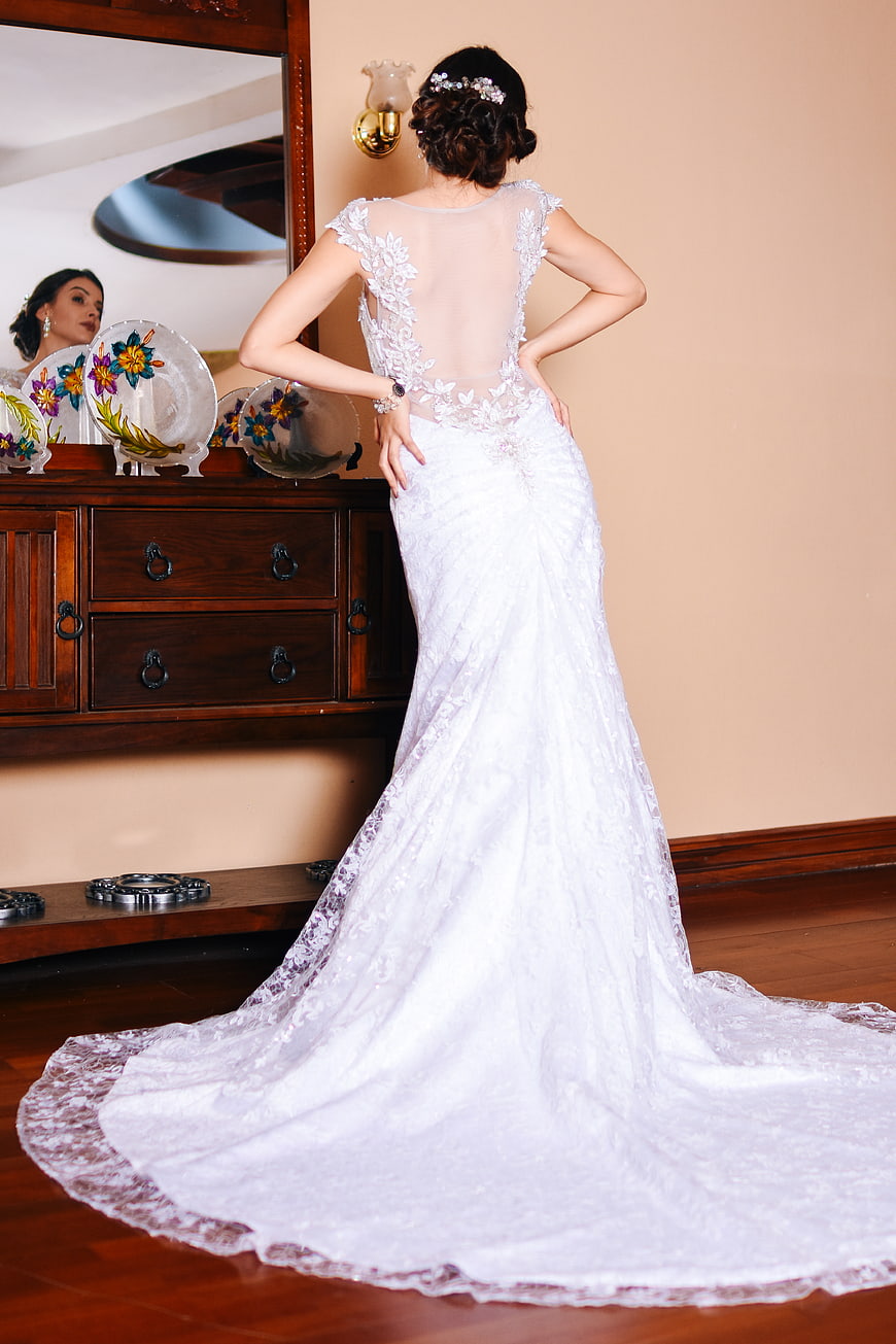 Bride in Lace Wedding Dress Standing by Mirror