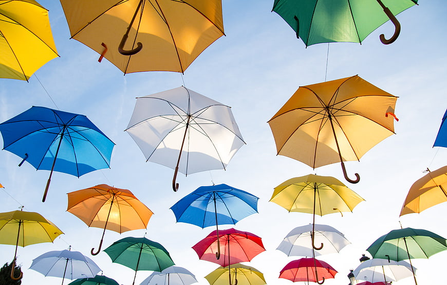 Colorful umbrellas hanging against a blue sky