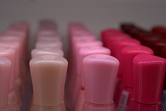 Rows of pink and red nail polish bottles on a shelf