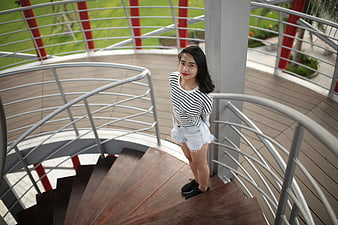 Young Woman in Striped Top on Spiral Staircase