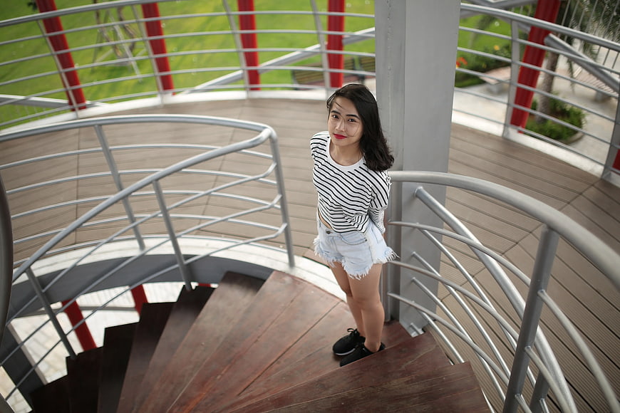 Young Woman in Striped Top on Spiral Staircase