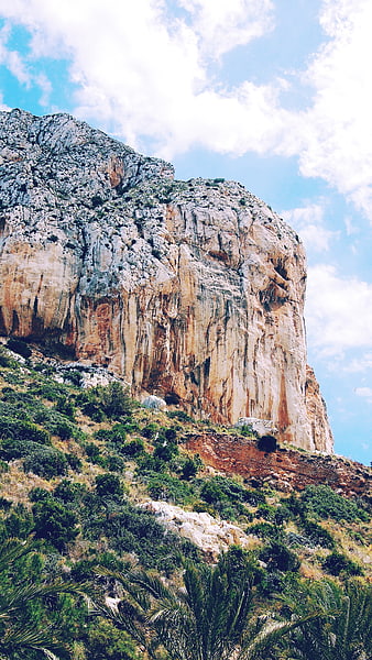 Majestic Rocky Mountain Cliff with Blue Sky and Clouds