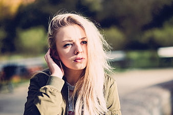 Blonde Woman in Olive Jacket Looking at Camera Outdoors