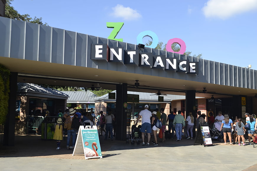 Crowded Zoo Entrance With Colorful Signage And Visitors