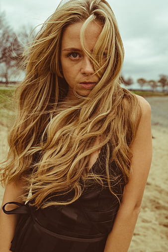 Blonde Woman with Windblown Hair on Sandy Beach