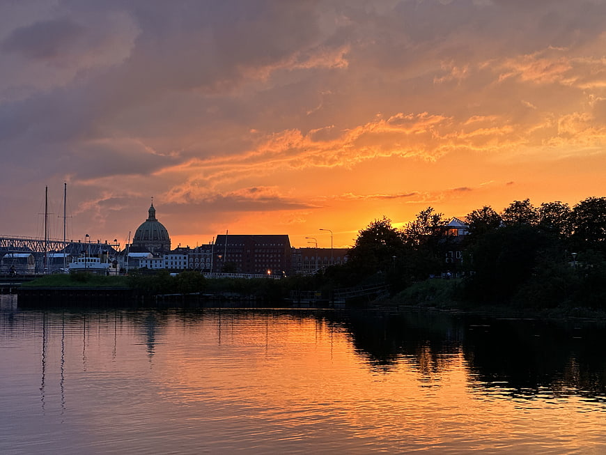 Vibrant orange sunset over city skyline with water reflections