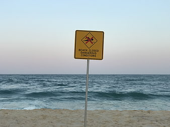 Beach closed sign on rough ocean shore