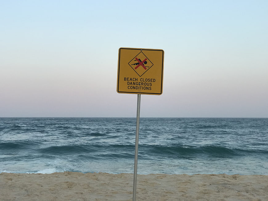 Beach closed sign on rough ocean shore
