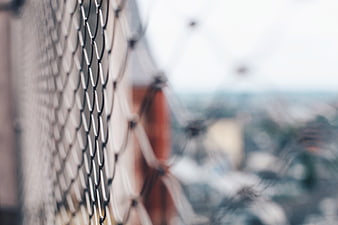 Close-up of black wire mesh fence with blurred background