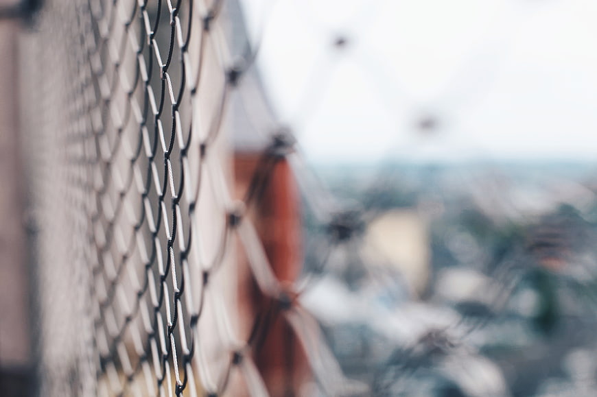 Close-up of black wire mesh fence with blurred background
