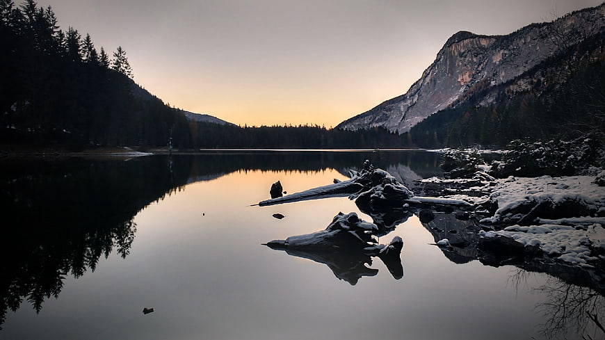 Serene Winter Lake with Snowy Mountains and Driftwood