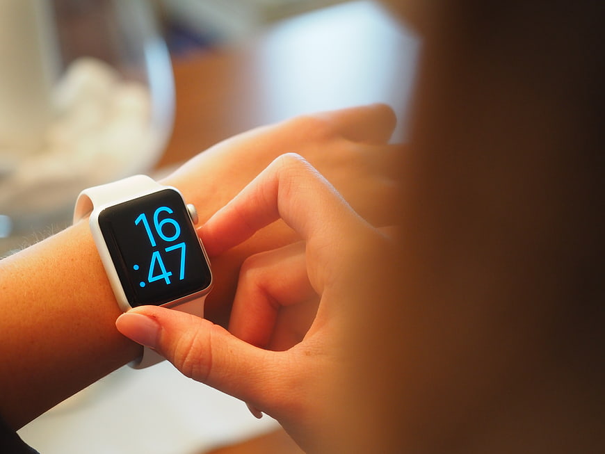 Close-up of woman checking time on white smartwatch