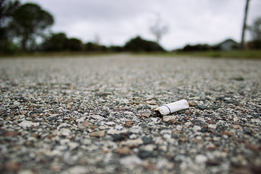 Cigarette butt lying on asphalt road surface
