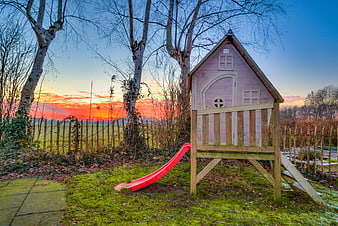 Pink Wooden Playhouse with Red Slide at Sunset