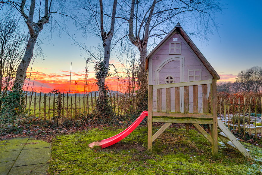 Pink Wooden Playhouse with Red Slide at Sunset