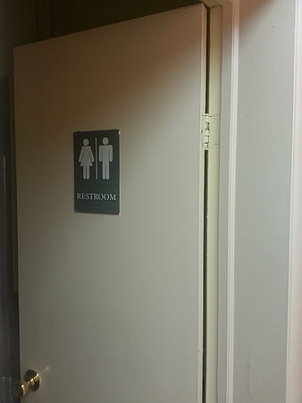 Restroom door with unisex sign and brass knob